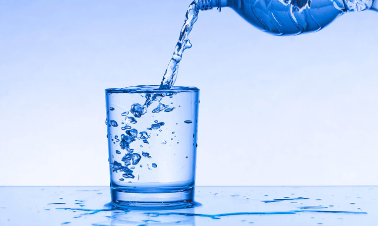 Drinking water is poured from a bottle into a glass