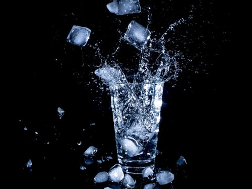glass-of-water-with-ice-cubes-falling-in-and-splashing-against-black-background