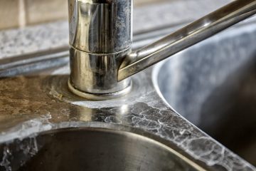 Close-up of a kitchen tap and sink with hard water calcification