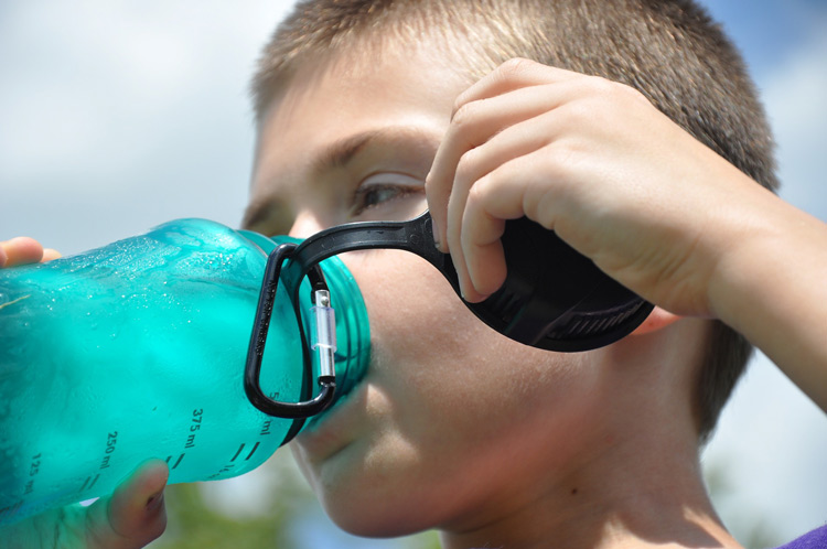 boy-drinking-ice-water-out-of-blue-reusable-water-bottle