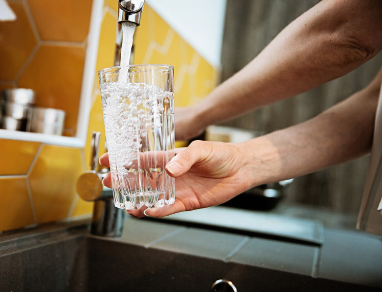 hand-holding-glass-filling-with-water-at-kitchen-faucet