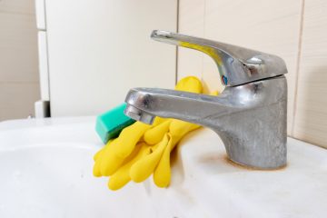 faucet-with-mineral-deposits-from-hard-water-with-yellow-rubber-gloves-and-sponge-on-edge-of-sink