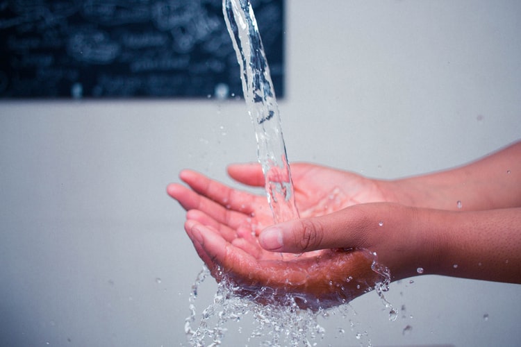 two-hands-cupping-stream-of-filtered-water-coming-from-faucet