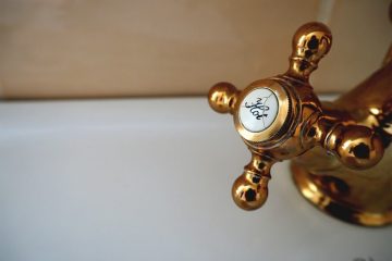 gold-hot-water-faucet-in-bathtub-against-beige-wall