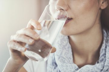 nose-down-cropped-photo-of-woman's-face-drinking-water-from-tall-clear-glass