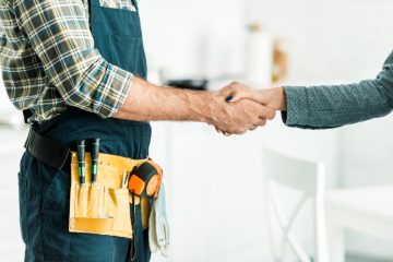 cropped image of plumber and client shaking hands in kitchen
