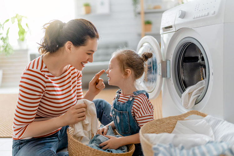 Mother and daughter in their laundry area washing clothes using softened water.