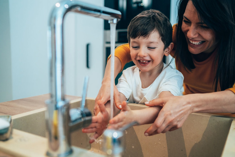 Soft water - Mother and son washing their hands in the kitchen using their home's soft water supply.