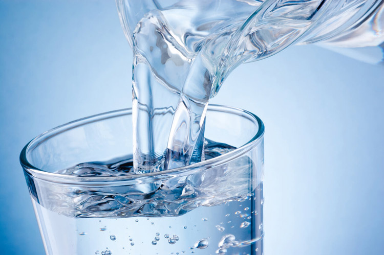 pouring-drinking-water-containing-e.-coli-from-jug-into-glass-on-blue-background