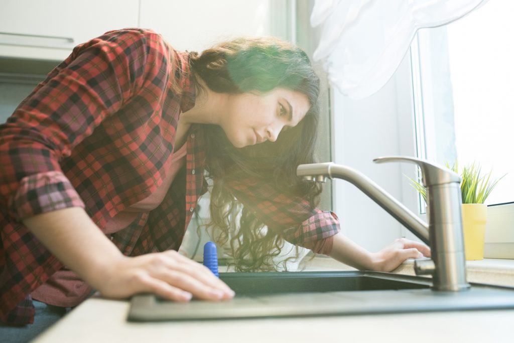 woman-checking-scale-problem-in-kitchen-faucet